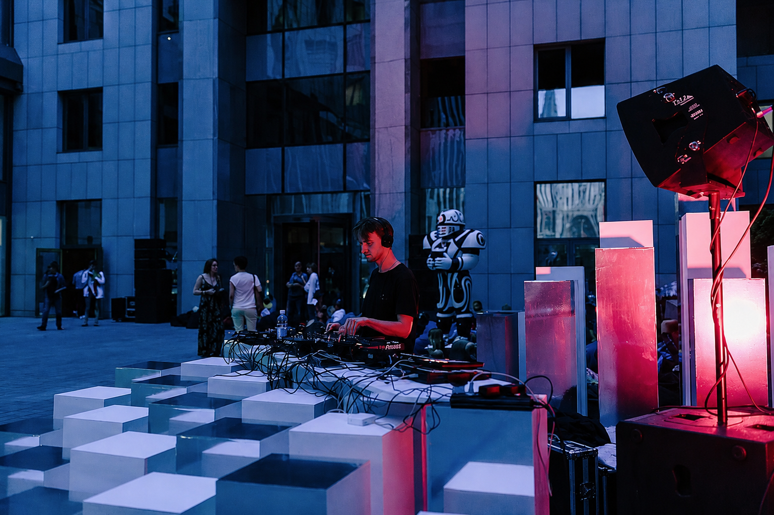 DJ tritt in der Abenddämmerung neben einer beleuchteten geometrischen Würfel-Installation auf