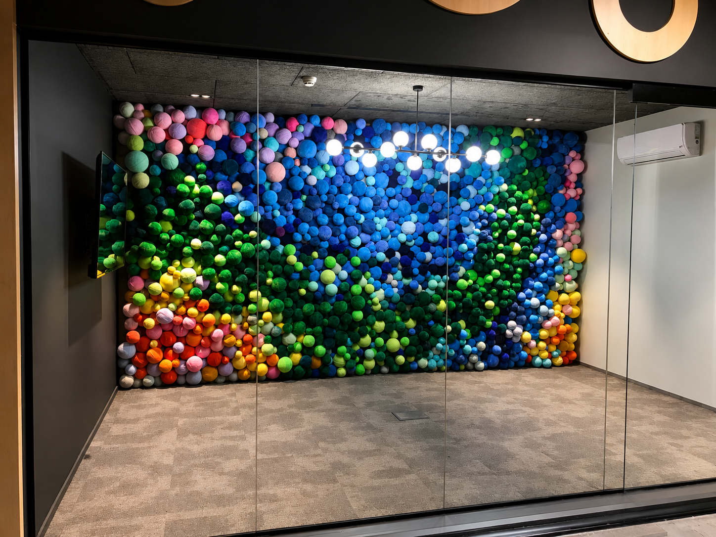 Die Wollwand hinter Glas in einem Meetingraum installiert, spiegelt den Kronleuchter darüber